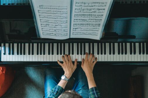 Person spielt Klavier, Klaviatur und Hände von oben zu sehen