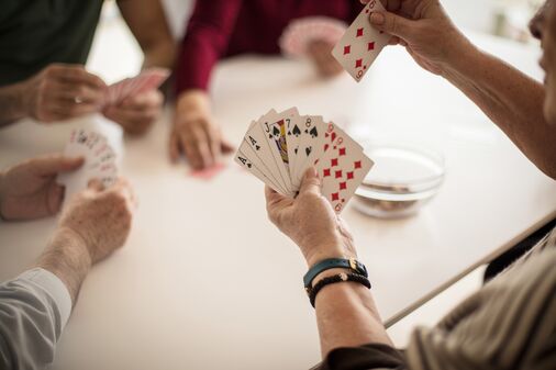 Einige Personen spielen Karten, Fokus auf Händen und Spielkarten